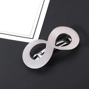Detail view of infinity-shaped silver matte hair clip with metal spring clamp on dark surface