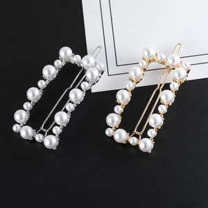 Detailed macro of gold and silver rectangle hair clips with elegant inlaid faux pearls