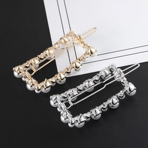 Detail view of rectangular hair clips with white pearls and rhinestones in gold and silver