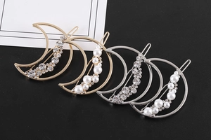 Détail macro de barrettes à cheveux lune avec perles et strass sur fond noir lisse