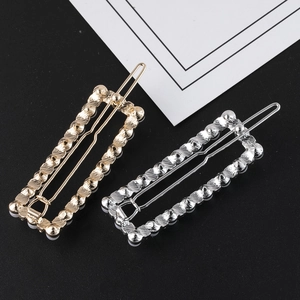 Detailed view of hollow rectangular metal hair pins in gold and silver with wave texture