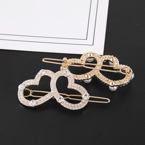 Dettaglio dei fermagli a forma di cuore con strass brillanti e perle raffinate
