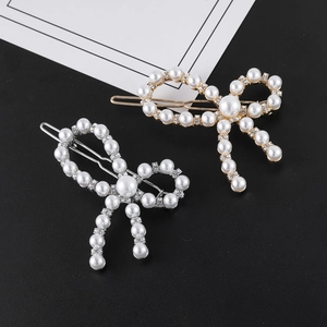 Détail de barrettes à nœud avec perles blanches et strass en finitions or et argent