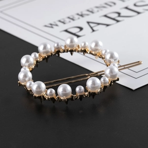 Détail d'une pince à cheveux ronde dorée ornée de perles et de strass brillants