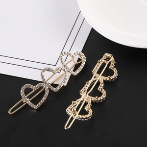 Détail de trois barrettes en forme de cœur dorées avec strass et accents de perles
