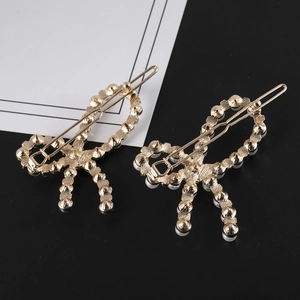 Détail des barrettes nœuds en alliage avec placage doré et perles blanches élégantes