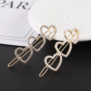 Gros plan de barrettes dorées en alliage avec perles et strass en forme de cœur