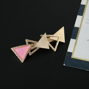 Goldener geometrischer Dreiecks-Haarclip mit rosa Glitzereinlage auf schwarzem Grund
