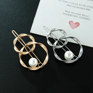 Detail of twisted double loop hair clips in gold and silver finish with white pearls