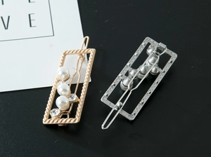 Detailed view of rectangular hair clips with gold twist texture, pearls and rhinestones