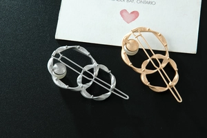 Detail of twisted metal hair clips in gold and silver finish with elegant white pearl accents