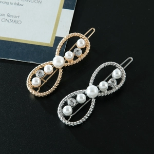Détail de pinces à cheveux en forme d'infini avec perles et strass sur fond noir élégant