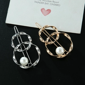 Detail of twisted metal hair clips in gold and silver with white pearls on a stylish card