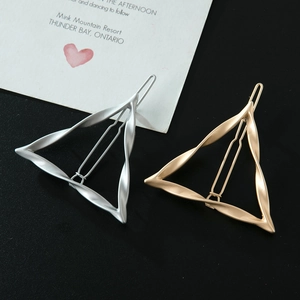 Dettaglio di fermagli per capelli a triangolo intrecciato in finiture oro e argento opaco