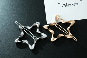 Detail van stervormige metalen haarspelden in goud en zilver met golvende textuur