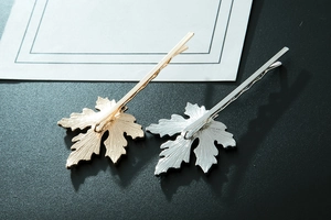 Détail macro de pinces à cheveux feuille d'érable dorées et argentées aux nervures texturées