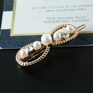 Détail d'une barrette infini en métal doré avec perles blanches et strass brillants