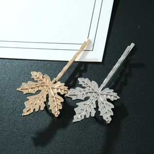 Barrettes à cheveux feuilles d'érable en métal doré et argenté sur fond sombre élégant