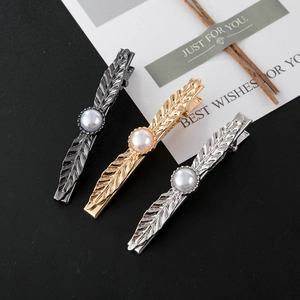 Three elegant feather-shaped hair clips in gold, silver, and gunmetal with pearls