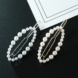 Gros plan de barrettes dorées et argentées au design ovale évidé orné de perles