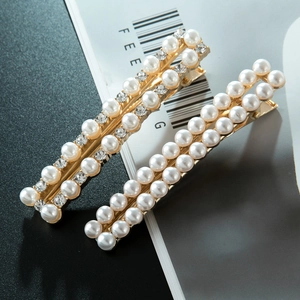 Détail de deux pinces à cheveux dorées ornées de perles et de strass blancs élégants