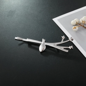 Chic silver bird on branch hair clip with star detail on a textured surface