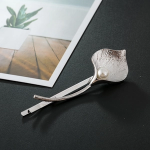 Minimalist silver tulip hair clip with white pearl on elegant textured black background