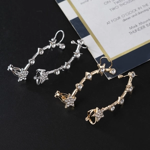 Detailed view of silver and gold star-shaped ear cuffs with sparkling crystals on black background