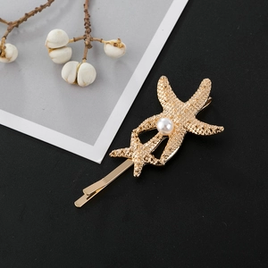 Pince à cheveux étoile de mer dorée avec perle centrale sur fond texturé élégant