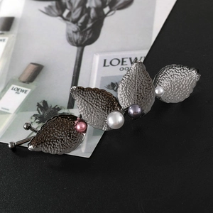 Close-up of vintage gun-black leaf hair clip featuring intricate veins and three colored pearls