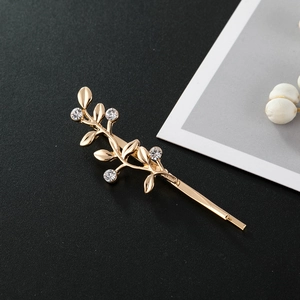 Pince à cheveux élégante en forme de branche dorée avec strass sur fond noir