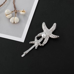 Détail d'une barrette étoile de mer argentée avec texture fine et insert en perle blanche