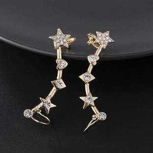 Close-up of gold star and heart ear cuffs featuring sparkling white rhinestones on black