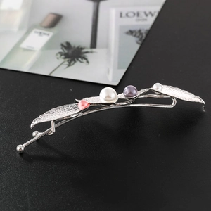 Detailed macro shot of silver leaf hair clip featuring colorful pearls on black texture