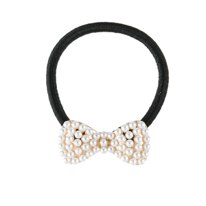 Detail of a black elastic hair tie featuring a pearl-studded gold bow accessory