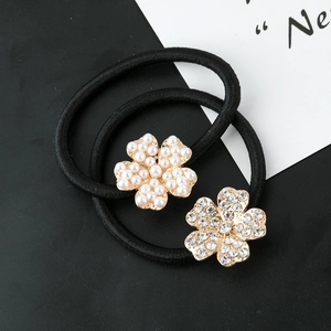 Détail de deux élastiques à cheveux avec fleurs en perles et strass sur base dorée