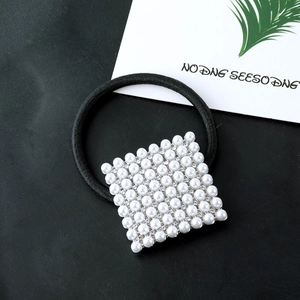 Square pearl and rhinestone hair tie with black high-elastic band on textured background