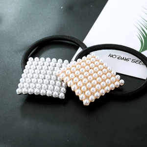 Detail of square hair ties featuring inlaid pearls and rhinestones on gold and silver bases