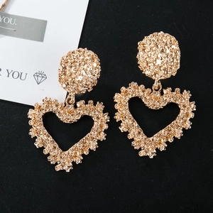 Detail of gold heart earrings with unique lava texture on a black background