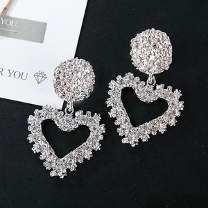 Detailed shot of silver textured lava-style oversized heart dangle earrings on a contrast background