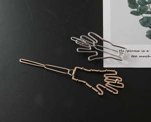 Détail des pinces à cheveux en forme de main évidée en finitions dorée et argent