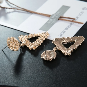 Detailed macro view of textured golden triangle earrings with irregular hammered finish