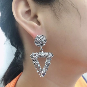 Close-up of silver triangle drop earrings with textured hammered finish on model