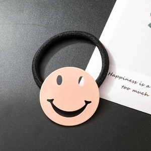 Vue détaillée de l'élastique à cheveux noir avec breloque smiley en or rose brossé