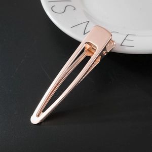 Detail of rose gold metal hair clip with brushed texture on black background