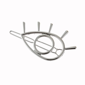 Polished silver metal eye shaped hair clip with eyelash design on white background