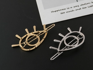 Detailed view of hollow evil eye hair clips in gold and silver finish with matte texture