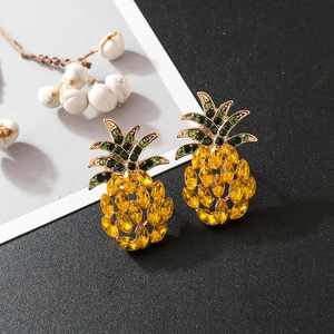 Détail de boucles d'oreilles ananas avec strass jaunes et verts éclatants