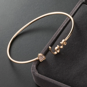 Close-up of gold LOVE heart open bangle with sparkling cubic zirconia pavé setting