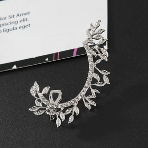 Detail view of silver hollow leaf ear cuff with sparkling crystals on black matte surface